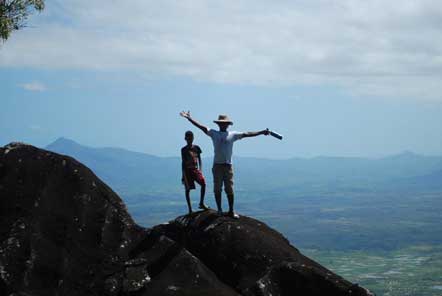 Man with hat and boy standing on top of moutain