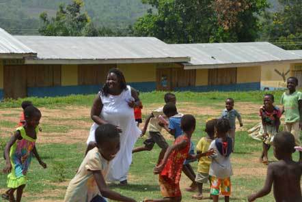 Lady srrounded by chilren playing in Africa 