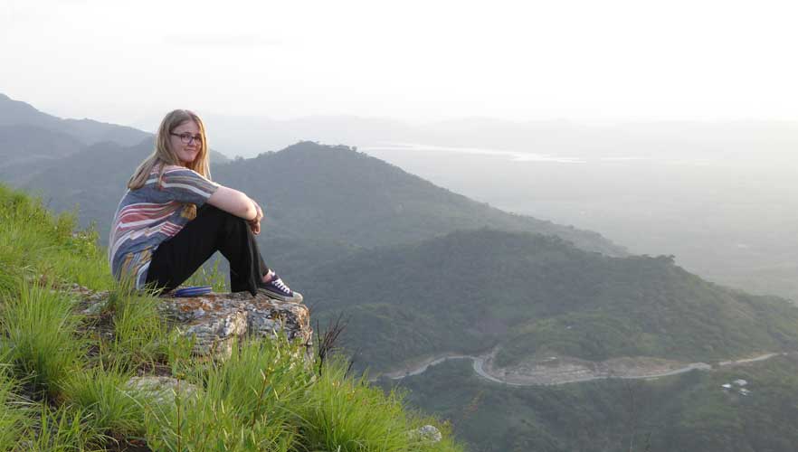 Volunteer sitting on a rock looking out over the mountains 