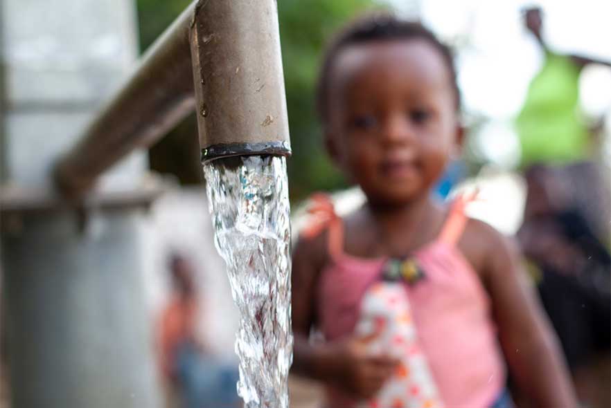 Child in Africa next to tap running water 