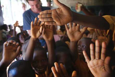 Children's hands in the air in Ghana in front of volunteer 